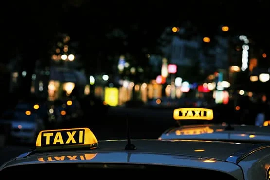 Deux lumignons « TAXI » se détachent dans une rue de nuit.