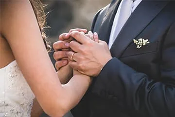 Un couple de mariés se tient les mains, en gros plan.