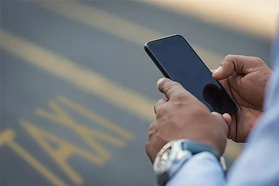 Gros plan sur des mains utilisant un smartphone dans la rue.