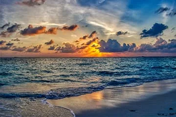 Vagues sur une plage au coucher du soleil.